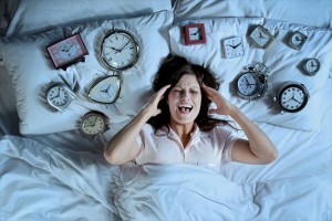 Woman in bed surrounded by alarm clocks